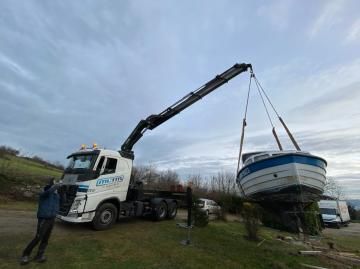 Un camion blanc suspend un petit bateau