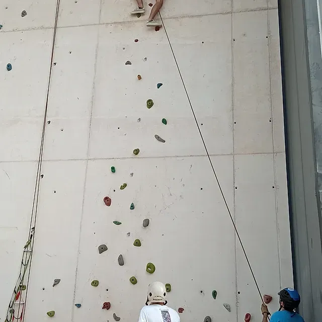 Un hombre que lleva un casco está escalando una pared de roca.