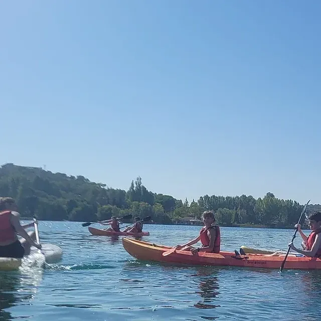 Un grupo de personas están remando en kayaks en un lago.
