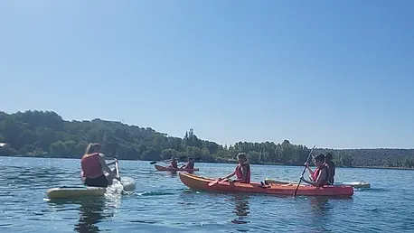 Un grupo de personas están remando en kayaks en un lago.