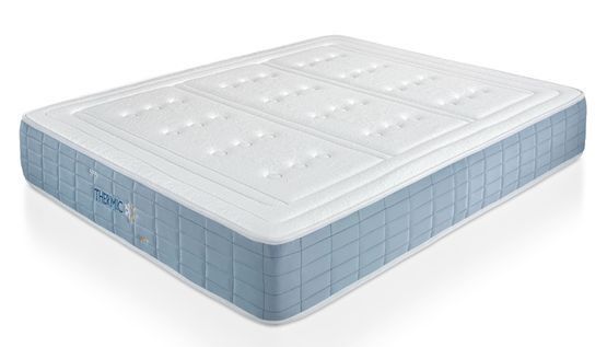 Un colchón blanco y azul está sobre una superficie blanca.