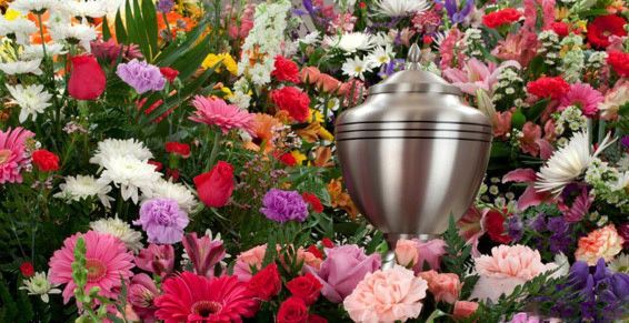 Urne funéraire en argent entourée d'un assortiment de fleurs colorées.