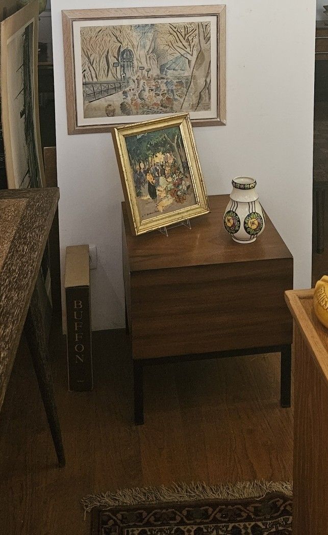 Une commode avec un tableau et un vase