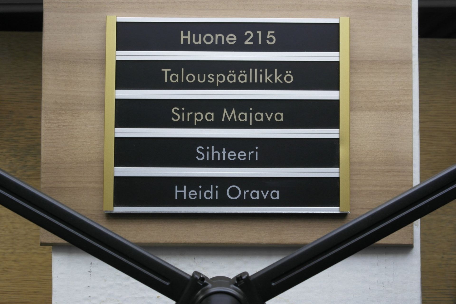 Office directory sign on a wall listing room 215, manager, Sirpa Mäyrävä, secretary, and Heidi Orava