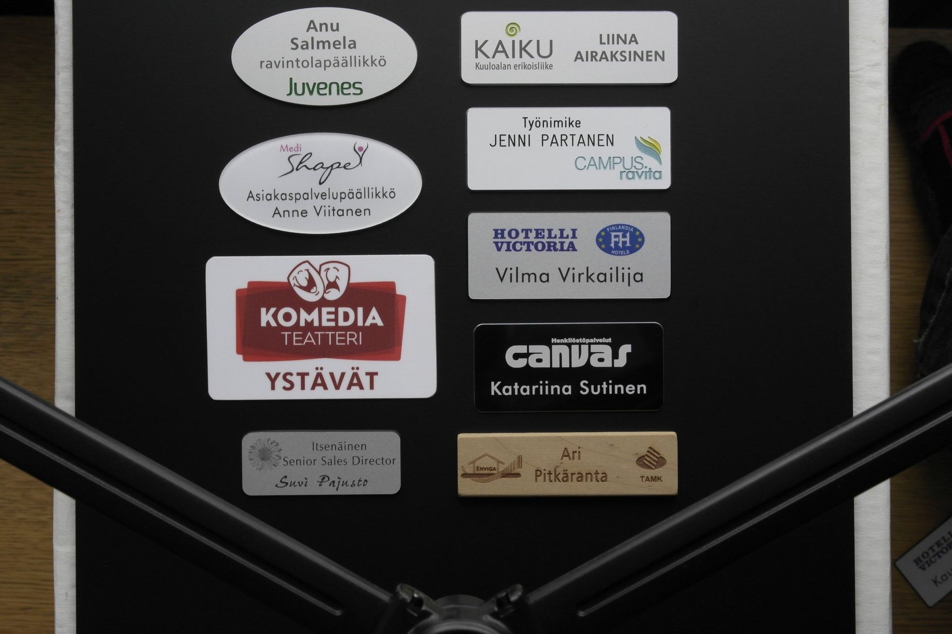 Ovi, jossa on useita suomenkielisiä pienyritysten kylttejä ja tarroja tumman kaiteen takaa.