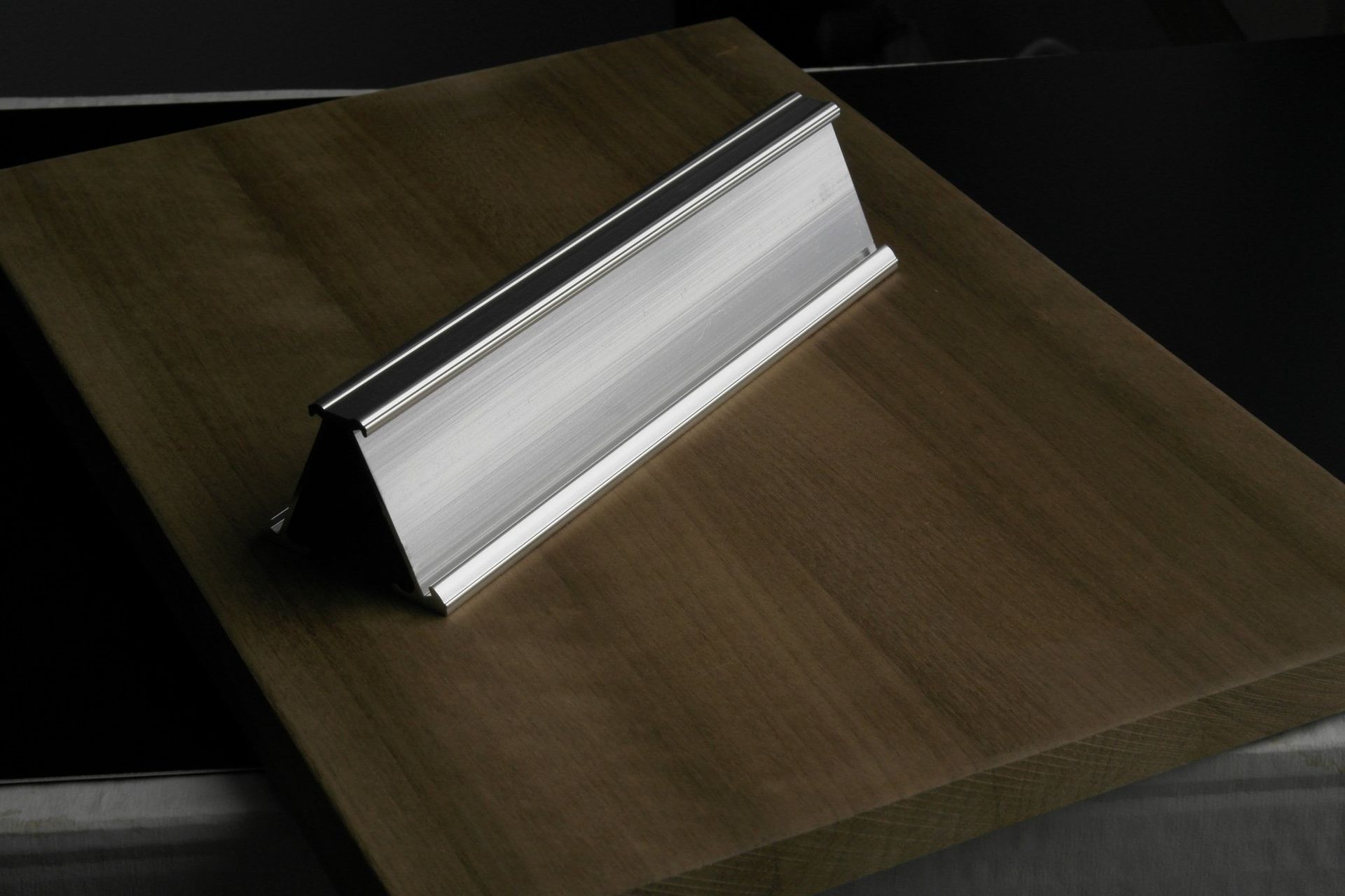 Puinen työpöytä, jonka keskellä on taitettu metallinen asiakirjateline.