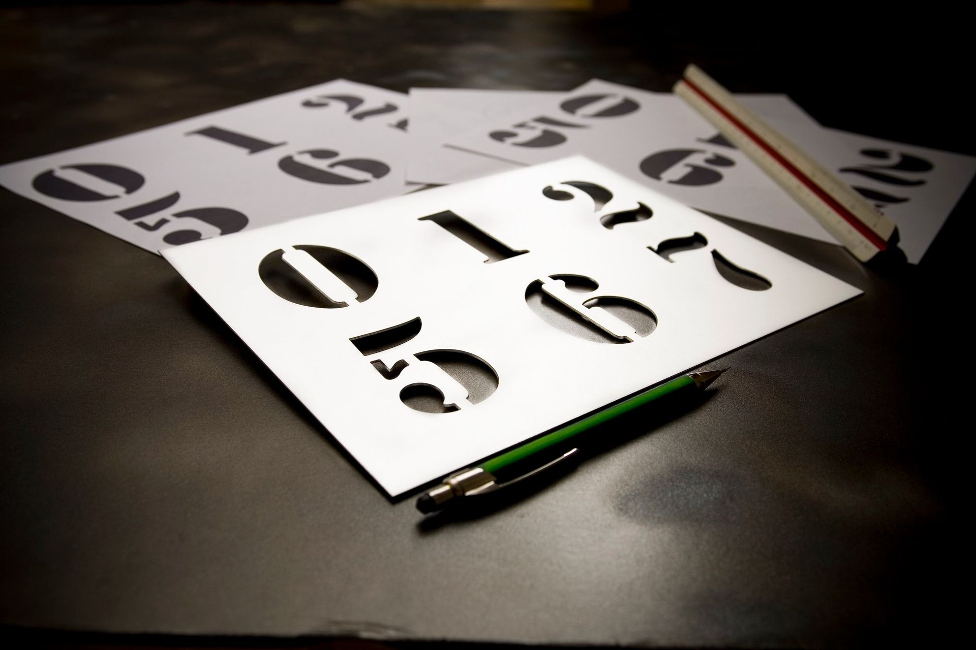 Pistekirjoitussapluunat tummalla pöydällä, lähellä valkoiset lakanat ja kynä