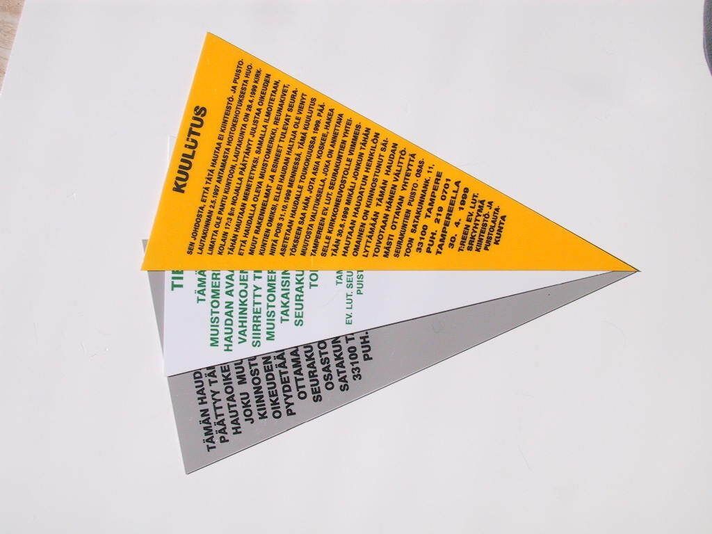 Kolme päällekkäistä taitettua paperikolmiota oranssina, valkoisena ja harmaana valkoisella taustalla.