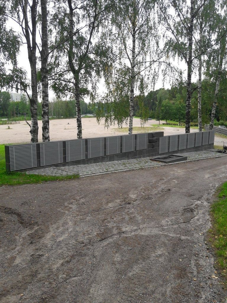 Koivuja maalatun betoniaidan vieressä sorapolulla puistossa