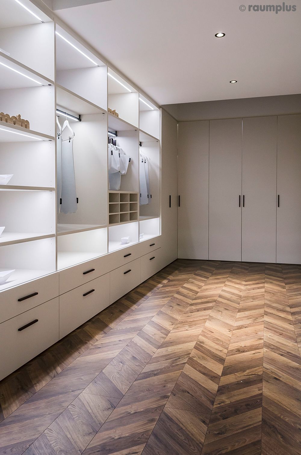 Ein begehbarer Kleiderschrank mit Holzboden und weißen Schränken