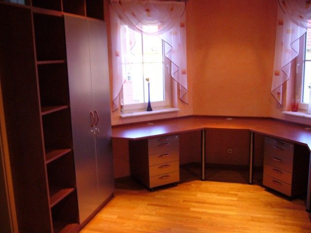 Ein Zimmer mit einem Schreibtisch und Schubladen und einem Fenster