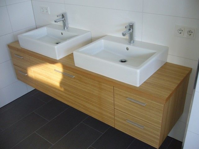 Zwei weiße Waschbecken auf einer Holzablage in einem Badezimmer