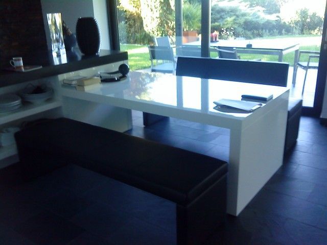 Ein Esszimmer mit einem weißen Tisch und einer schwarzen Bank