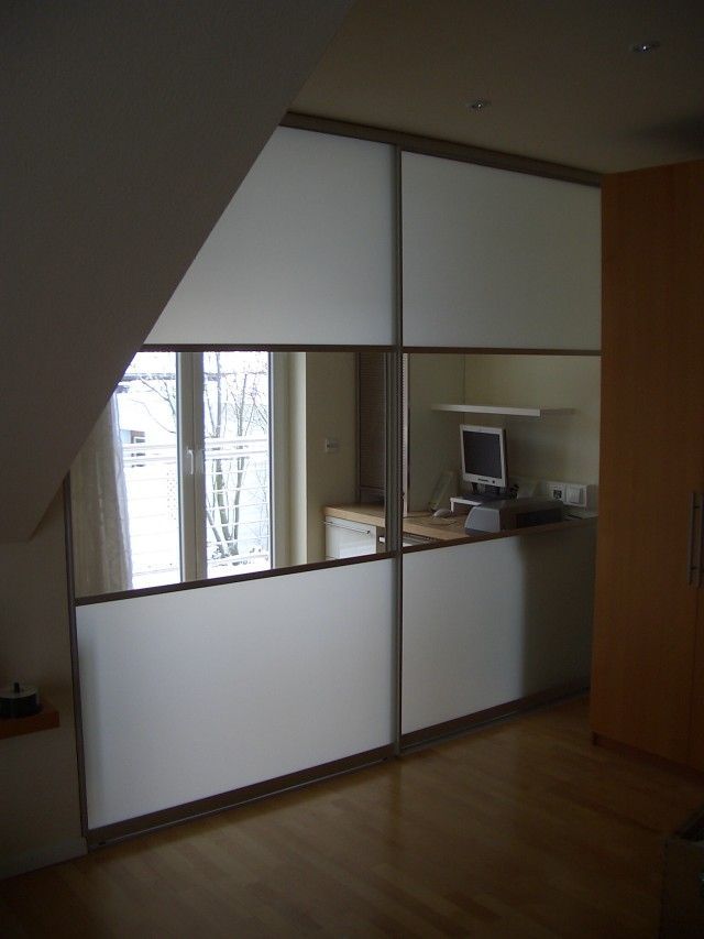 Ein Raum mit einer Glasschiebetür und einem Computer auf einem Schreibtisch