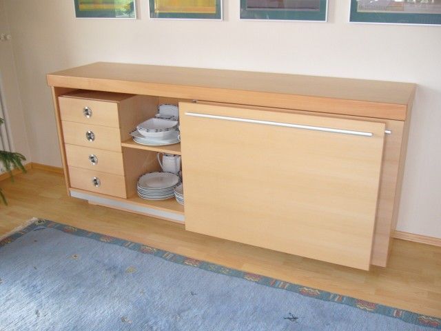 Ein Holzschrank mit Schubladen und Tellern auf den Regalen