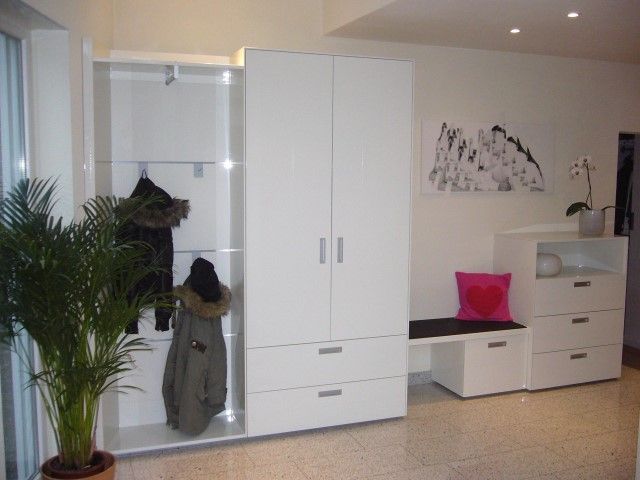 Ein weißer Kleiderschrank mit einem darin hängenden Mantel