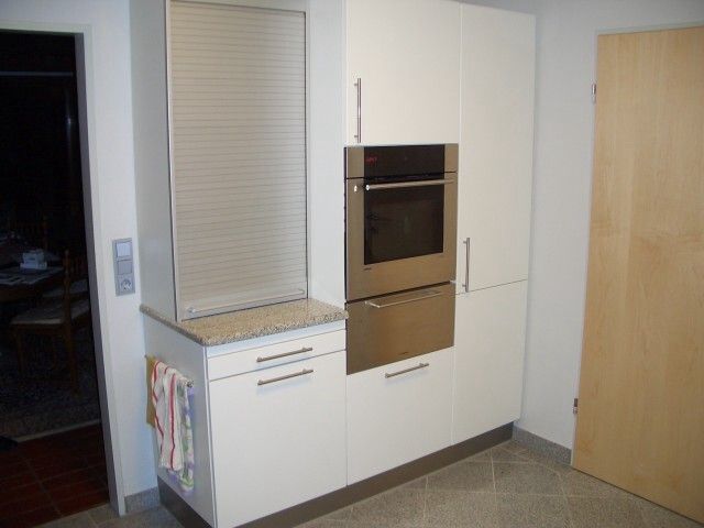 Eine Küche mit weißen Schränken und einem Edelstahlofen