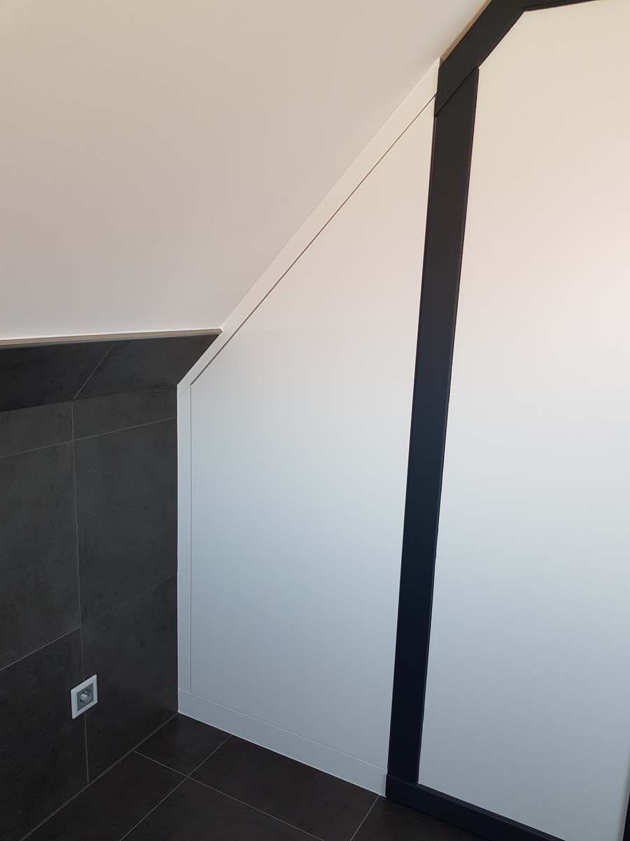 Eine Zimmerecke mit weißer Wand und schwarzen Zierleisten.