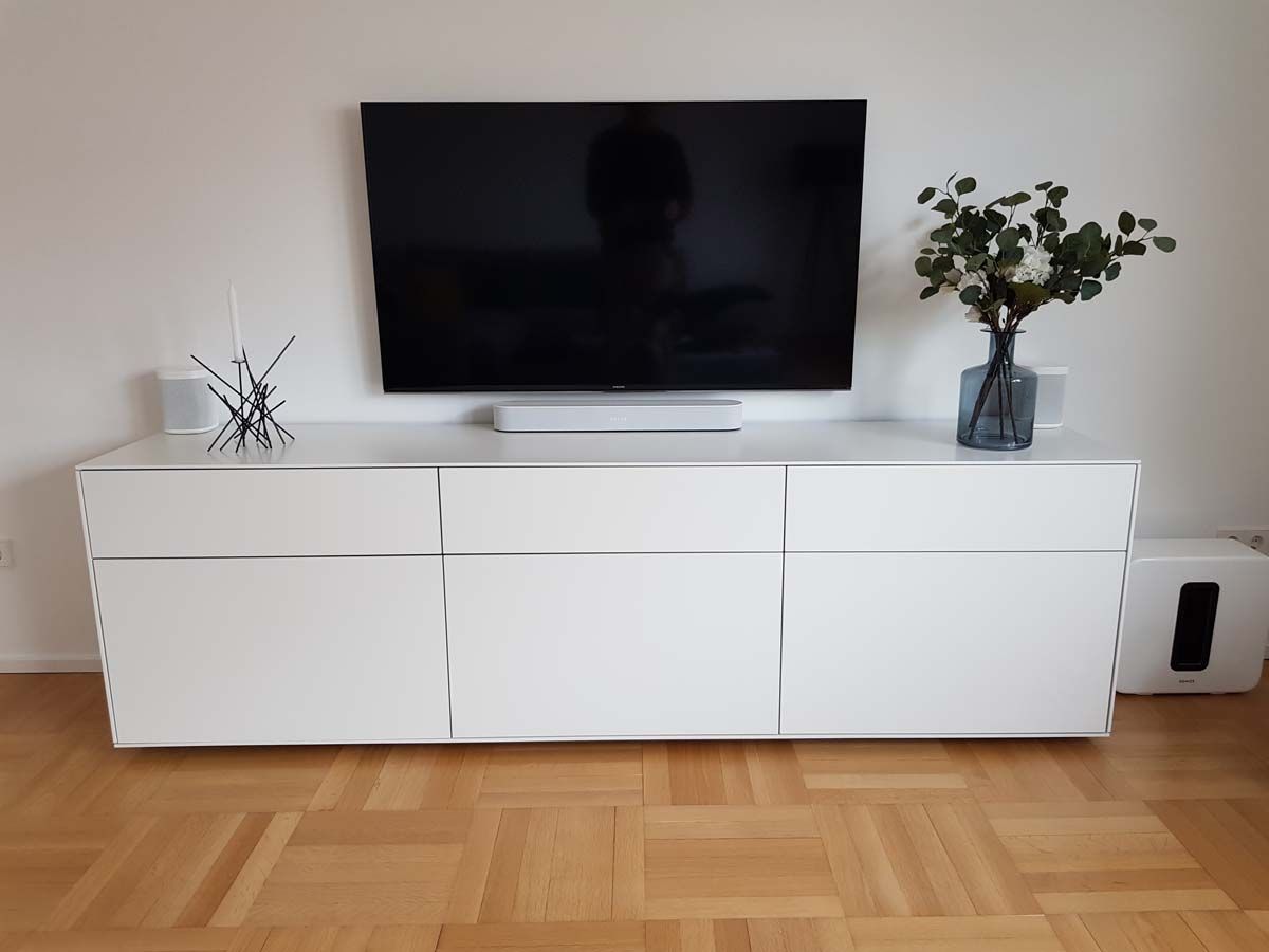 Ein weißes Entertainment-Center mit einem Flachbildfernseher und einer Vase mit Blumen