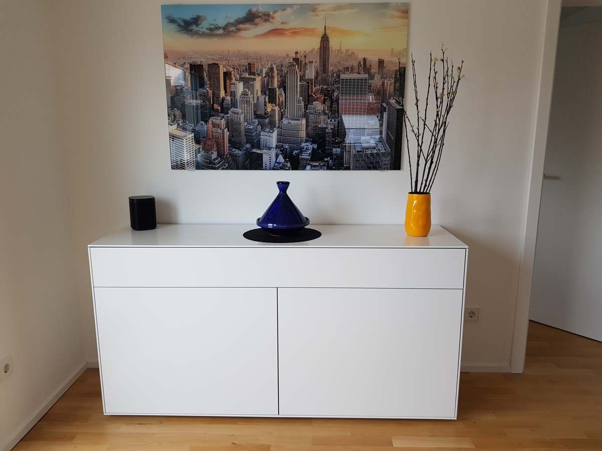 Eine weiße Kommode mit einem Gemälde an der Wand darüber