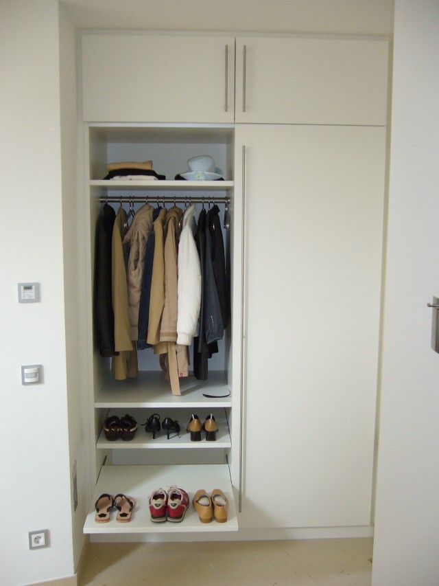 Ein weißer Schrank mit Kleidung und Schuhen auf Regalen