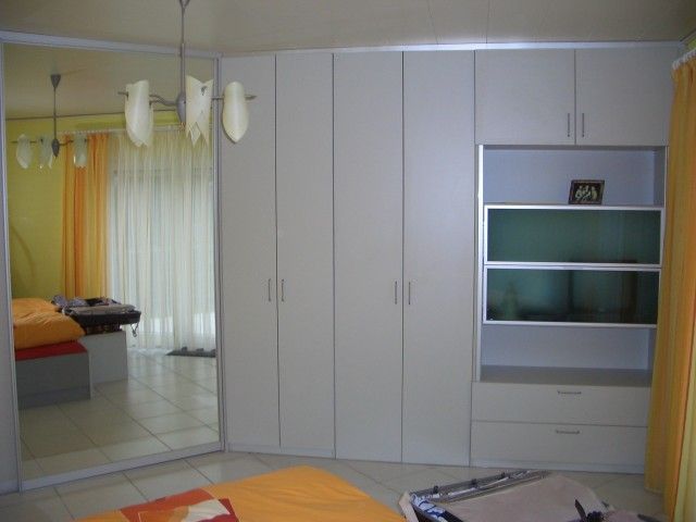 Ein Schlafzimmer mit weißen Schränken und einem großen Spiegel