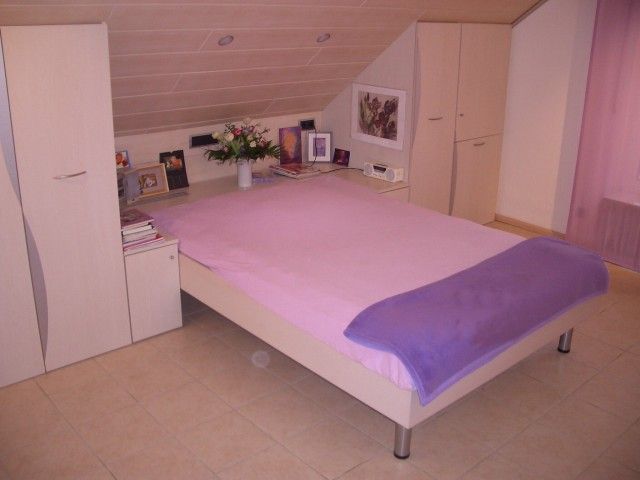 Ein Bett mit lila Laken und einer lila Decke in einem Schlafzimmer