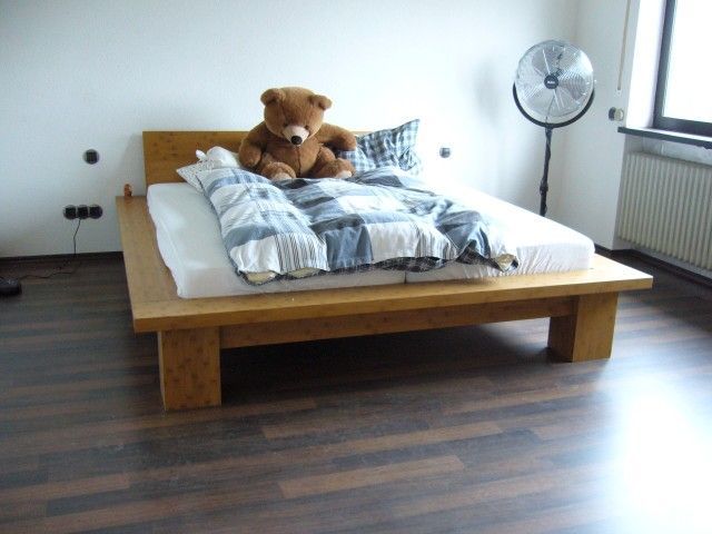 Ein Teddybär sitzt auf einem Bett neben einem Ventilator