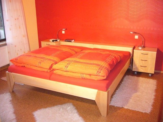 Ein Schlafzimmer mit einem Bett und zwei Nachttischen und einer roten Wand