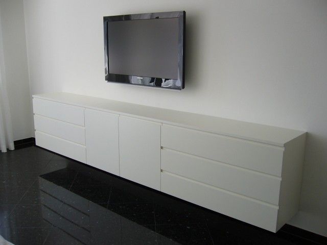 Ein Flachbildfernseher ist an der Wand über einer langen weißen Kommode montiert