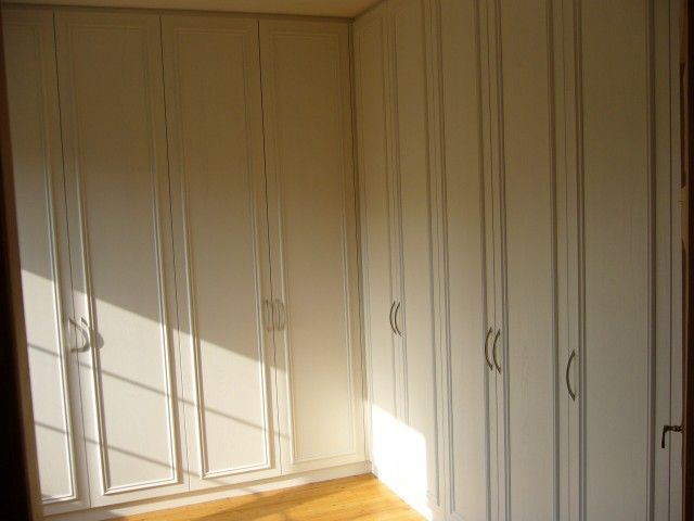 Ein Raum mit vielen weißen Schränken und einem Holzboden