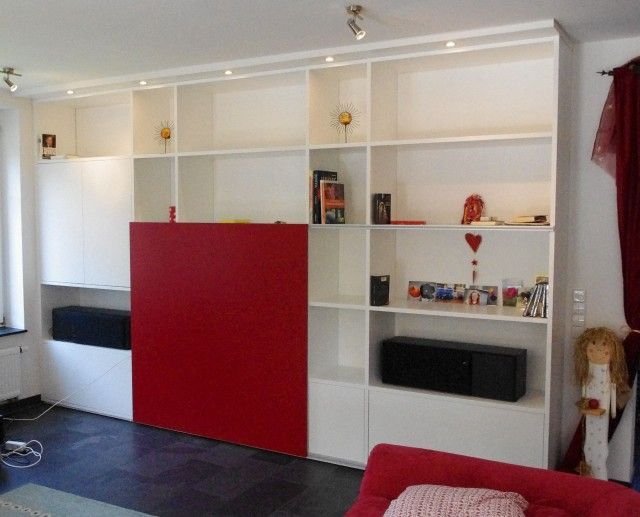 Ein Wohnzimmer mit weißen Regalen und einer roten Wand
