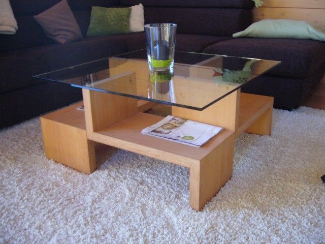 Ein Couchtisch mit Glasplatte und einer Zeitschrift darauf