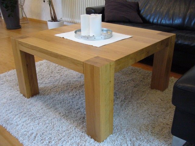 Ein Couchtisch aus Holz mit zwei Kerzen darauf in einem Wohnzimmer