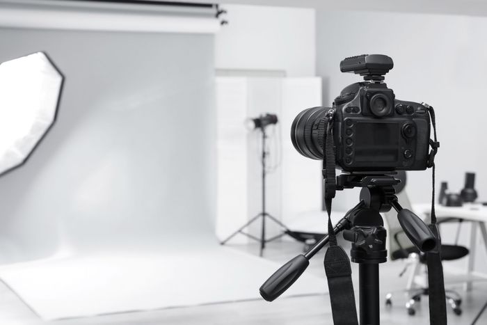 Kamera auf einem Stativ in einem Fotostudio, mit Hintergrund und Beleuchtungsausrüstung.