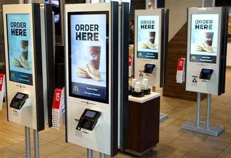 Quioscos de autoservicio para realizar pedidos en un restaurante, con letreros que dicen