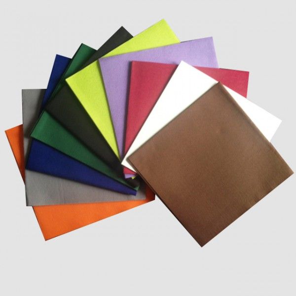 Une pile d'échantillons de tissu carrés de couleurs variées, notamment marron, orange, bleu, vert, jaune, violet, rouge et blanc.