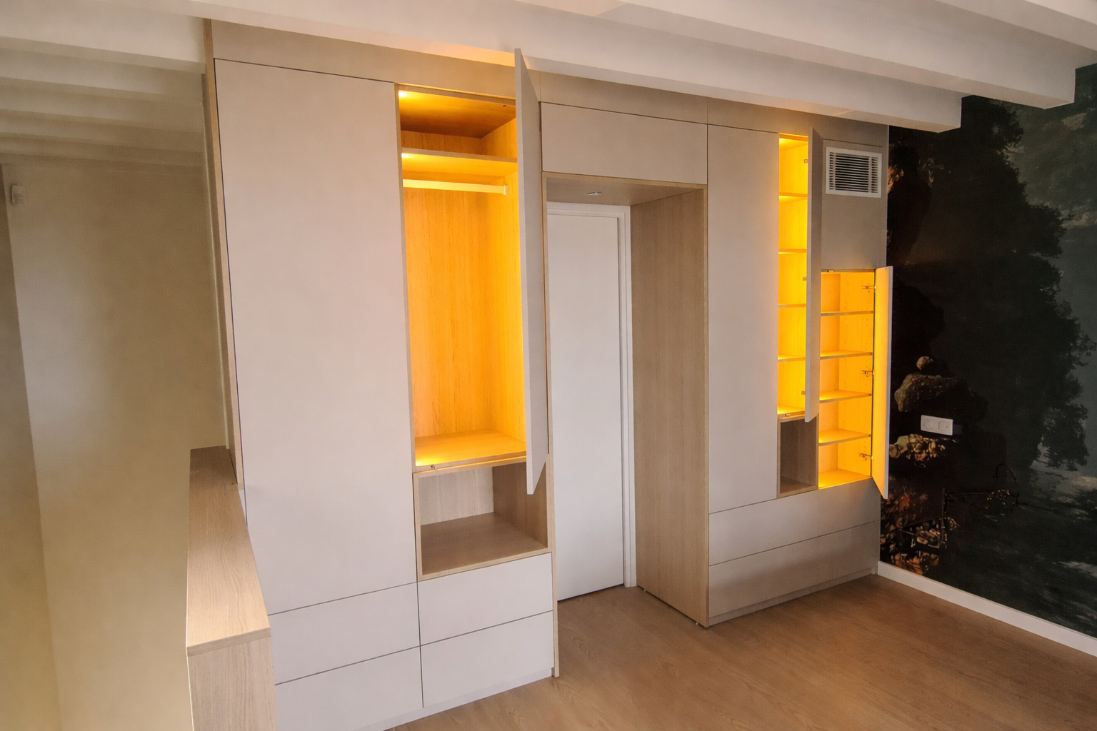 Une armoire moderne en bois clair avec étagères et tiroirs ouverts et éclairés, construite autour d'une porte dans une pièce minimaliste.