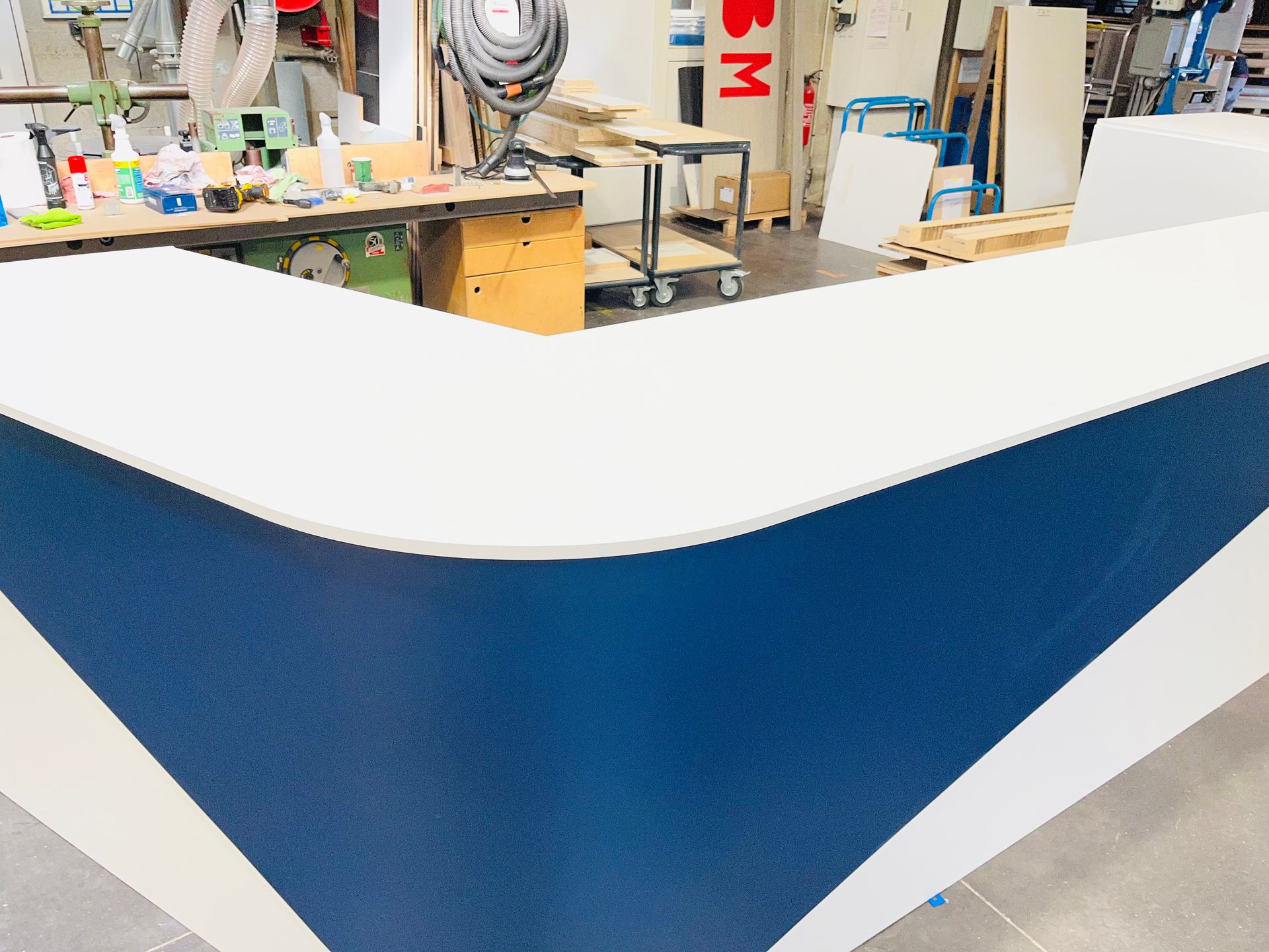 Comptoir blanc et bleu dans un atelier, bords arrondis.