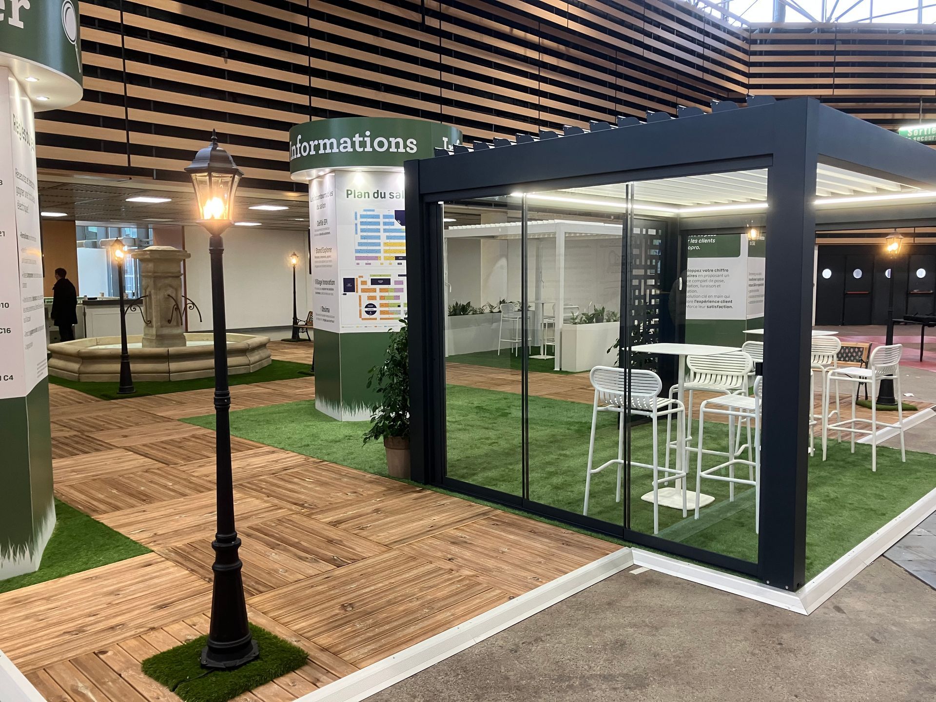 Aménagement extérieur avec terrasse, mobilier, gazon artificiel et lampadaire décoratif.