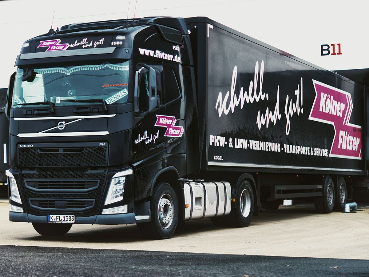 Ein schwarzer Volvo Sattelschlepper steht vor einem Gebäude