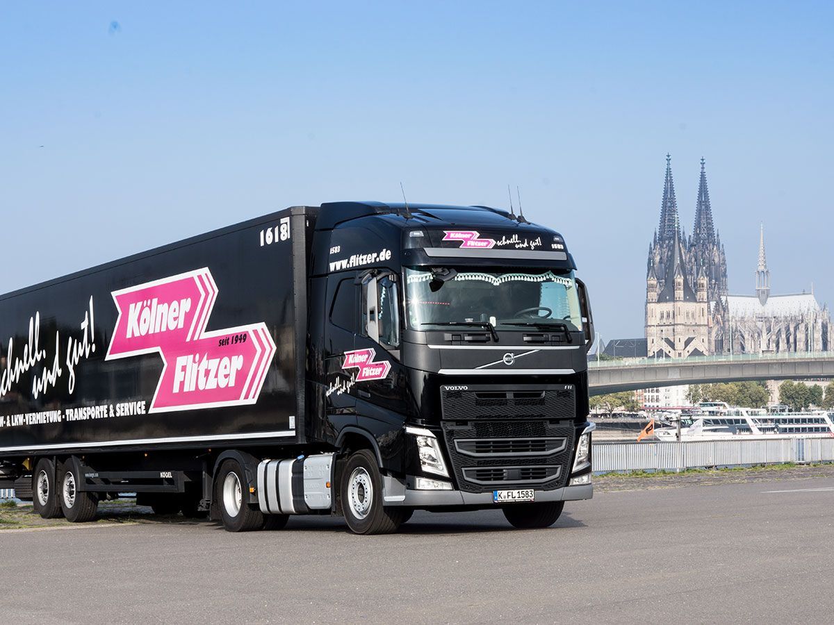 Ein schwarzer Lastwagen fährt auf einer Straße vor dem Kölner Dom entlang.