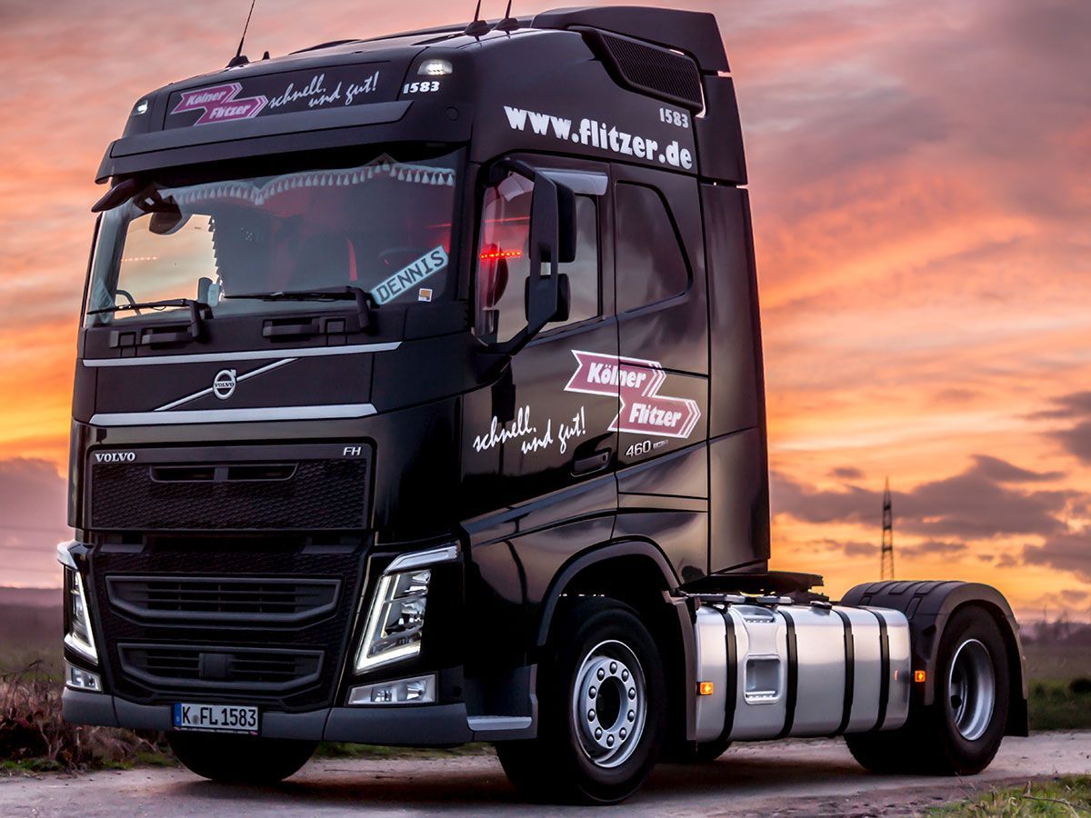 Bei Sonnenuntergang parkt ein schwarzer Sattelschlepper am Straßenrand.