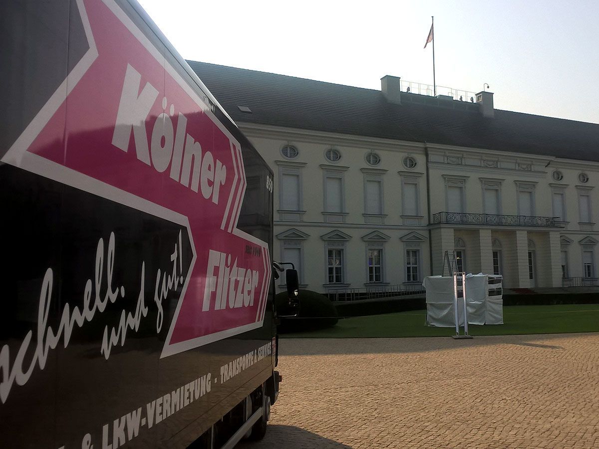 Ein schwarzer LKW mit einem roten Pfeil nach Köln