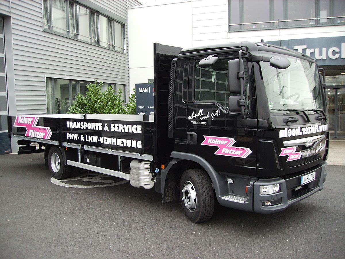 Ein schwarzer LKW steht vor einem Gebäude mit der Aufschrift „Truck“