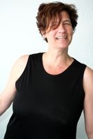 Eine Frau trägt ein schwarzes Tanktop und lächelt.