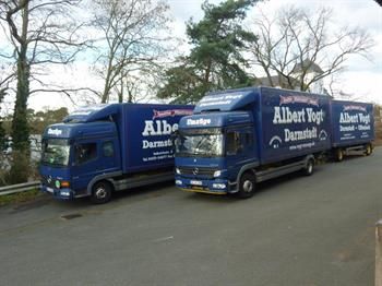 Drei blaue Lastwagen parken am Straßenrand.