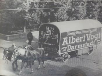 Ein Schwarzweißfoto von zwei Pferden, die einen Wagen ziehen.