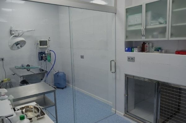Una sala de cirugía con una puerta corrediza de vidrio y un lavabo.
