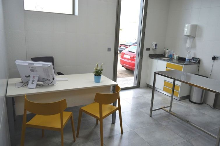 Una habitación con un escritorio y sillas y una computadora encima.